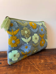 Floral-patterned pouch with tassel on a wooden surface