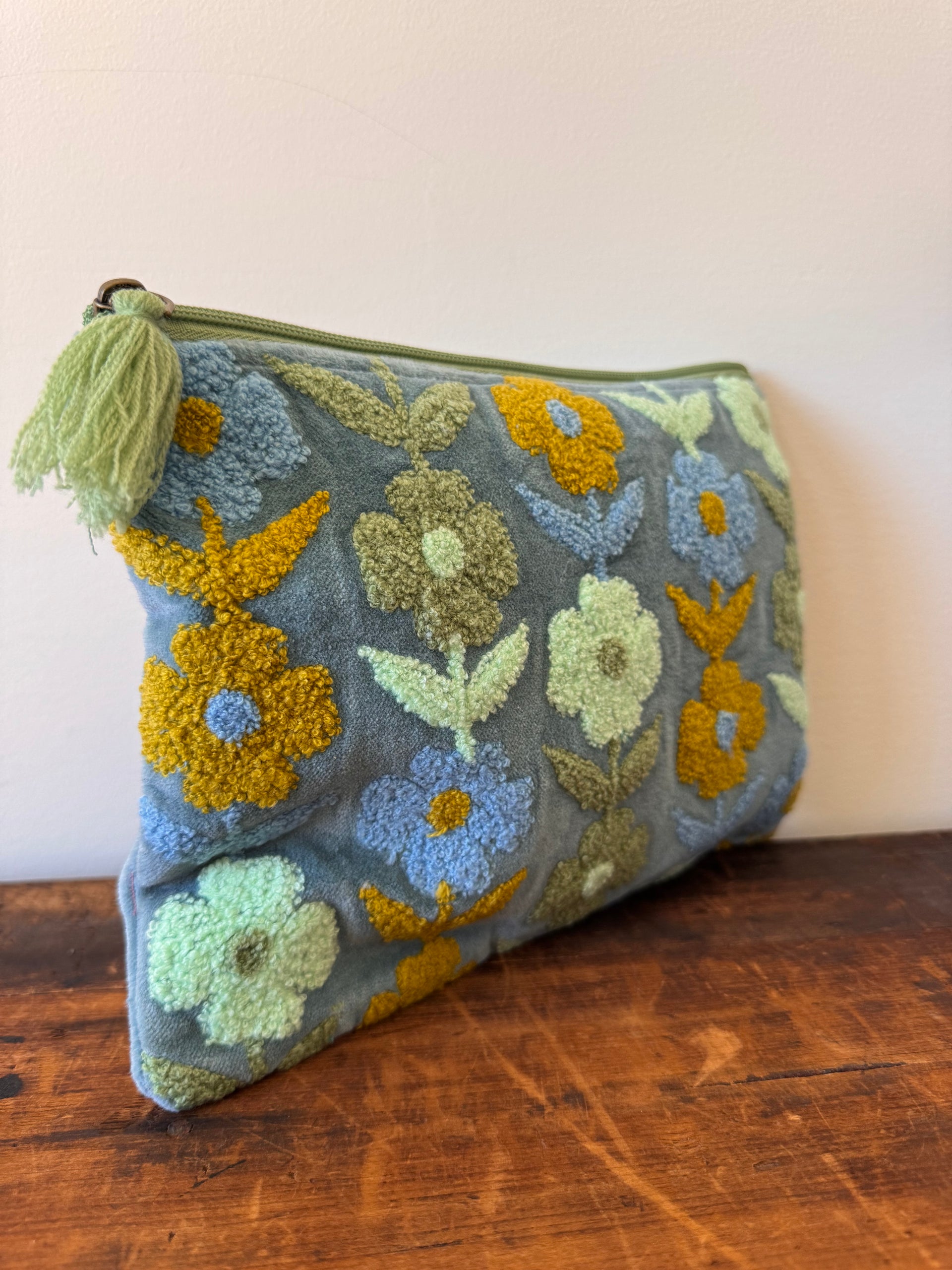 Floral-patterned pouch with tassel on a wooden surface