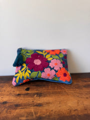 Colorful floral pouch with tassel on a wooden surface