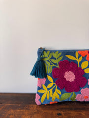 Floral embroidered clutch with tassel on a wooden surface