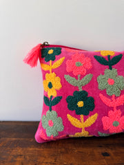 Colorful floral-patterned pillow with tassel on a white surface