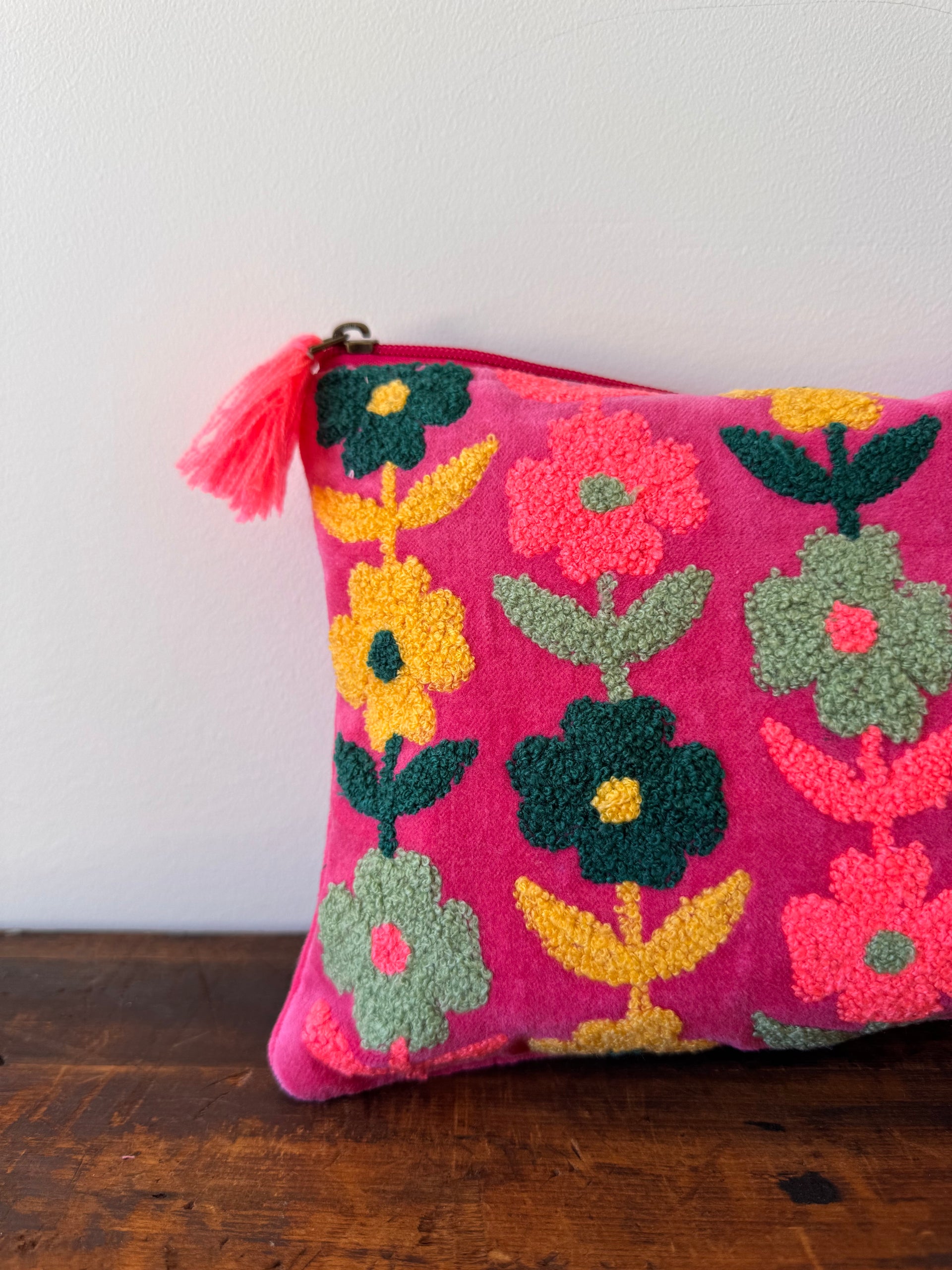 Colorful floral-patterned pillow with tassel on a white surface