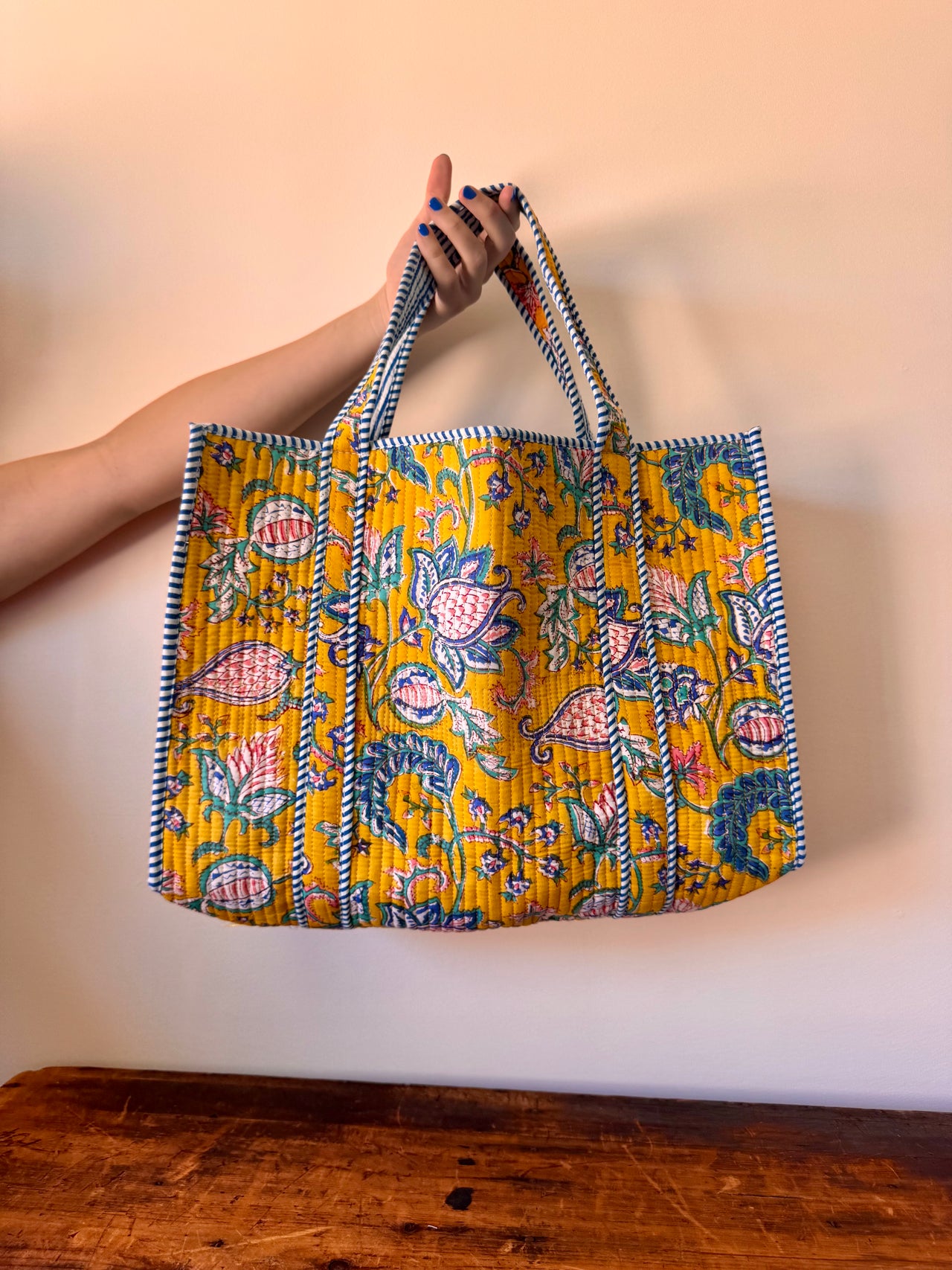 Handmade bag with floral pattern held by a person against a plain background