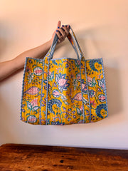 Handmade bag with floral pattern held by a person against a plain background