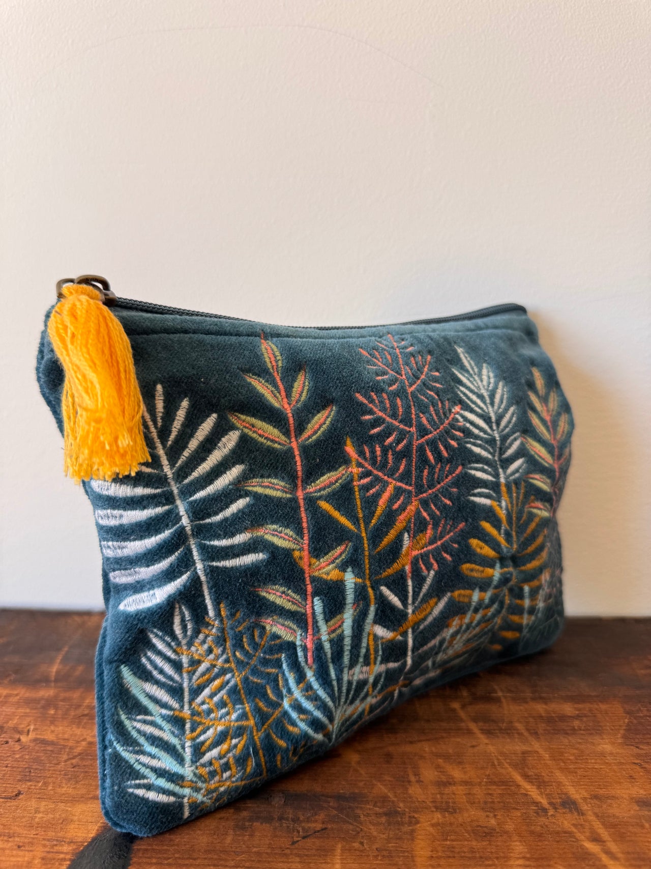 Decorative pillow with leaf pattern and tassel on a wooden surface