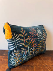 Decorative pillow with leaf pattern and tassel on a wooden surface