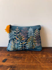 Blue pouch with floral pattern and yellow tassel on a wooden surface