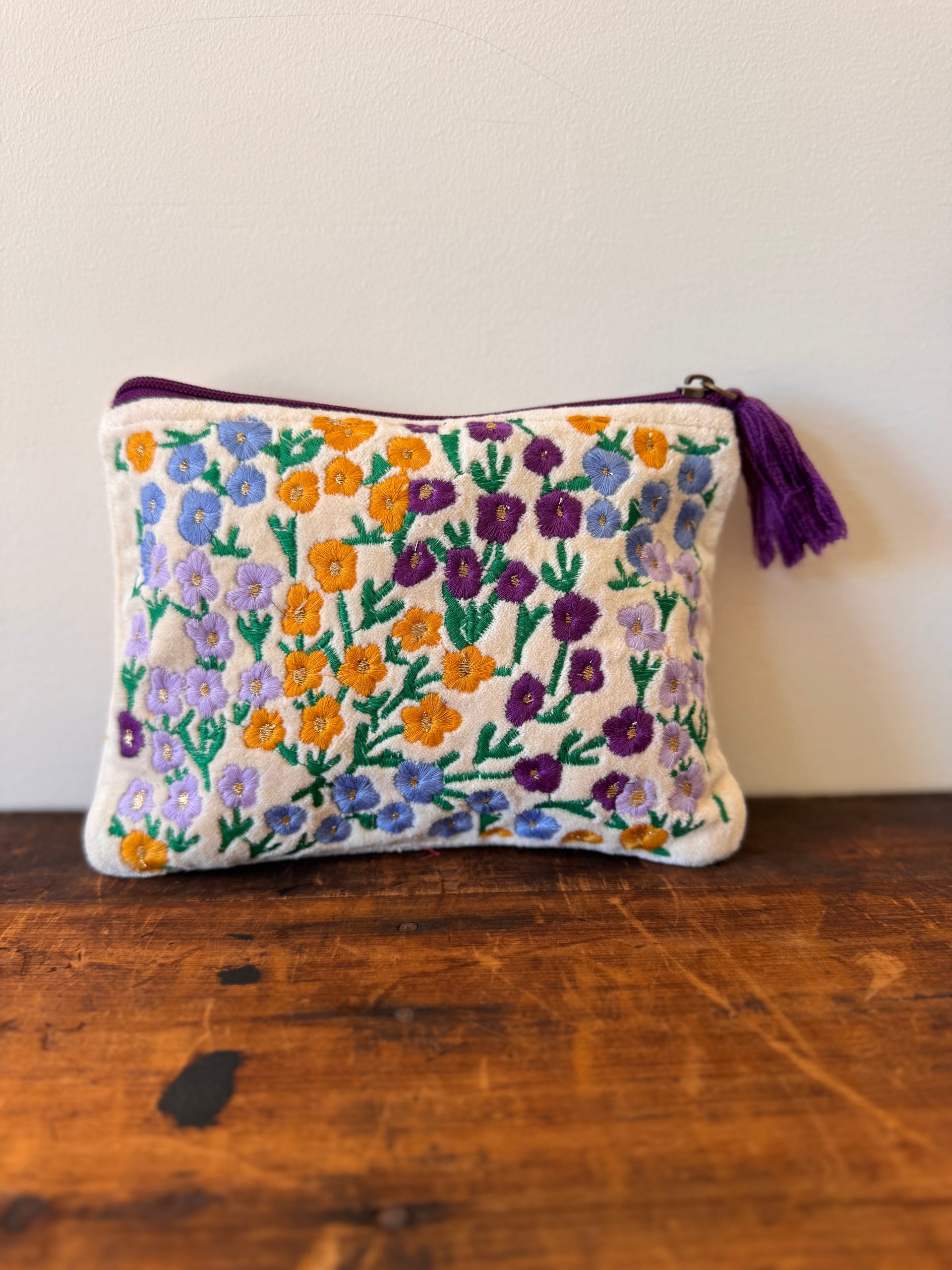 Embroidered floral pouch with a tassel on a wooden surface