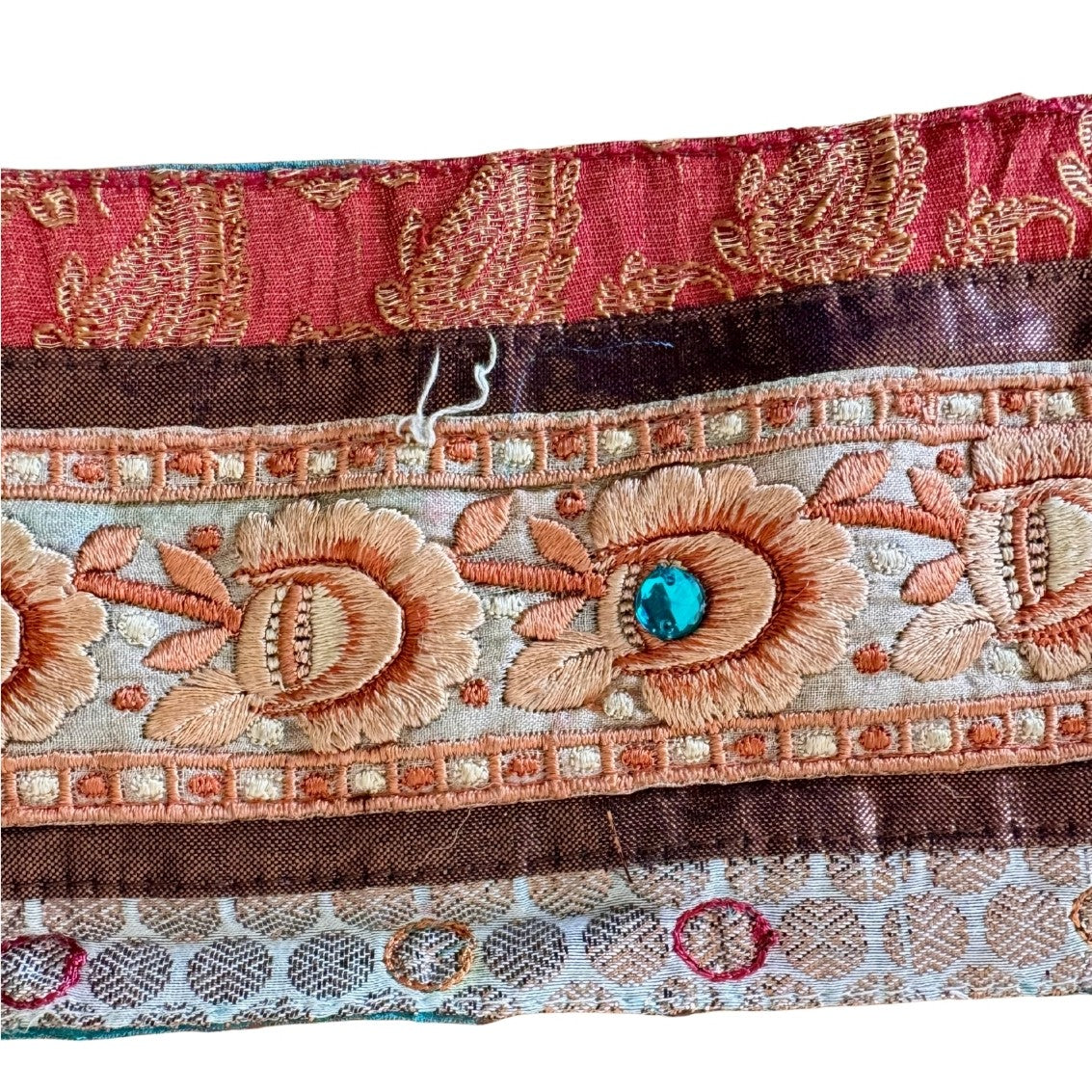 Close-up of decorative fabric with floral patterns and a turquoise stone.