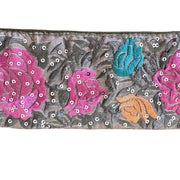 Decorative fabric strip with floral patterns and sequins on a white background