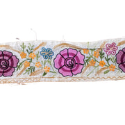 Embroidered floral ribbon with pink roses and green leaves on a white background
