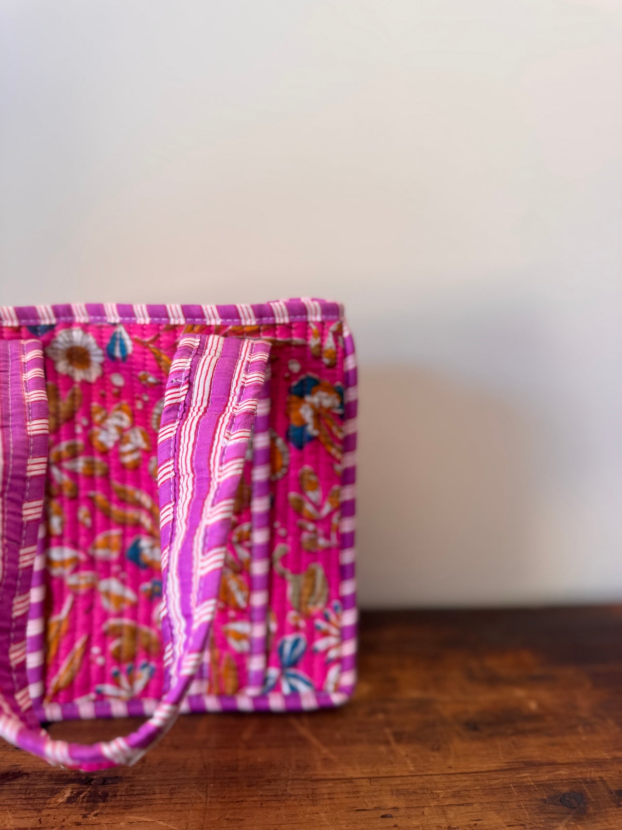 Two pink fabric bags with floral patterns on a wooden surface.