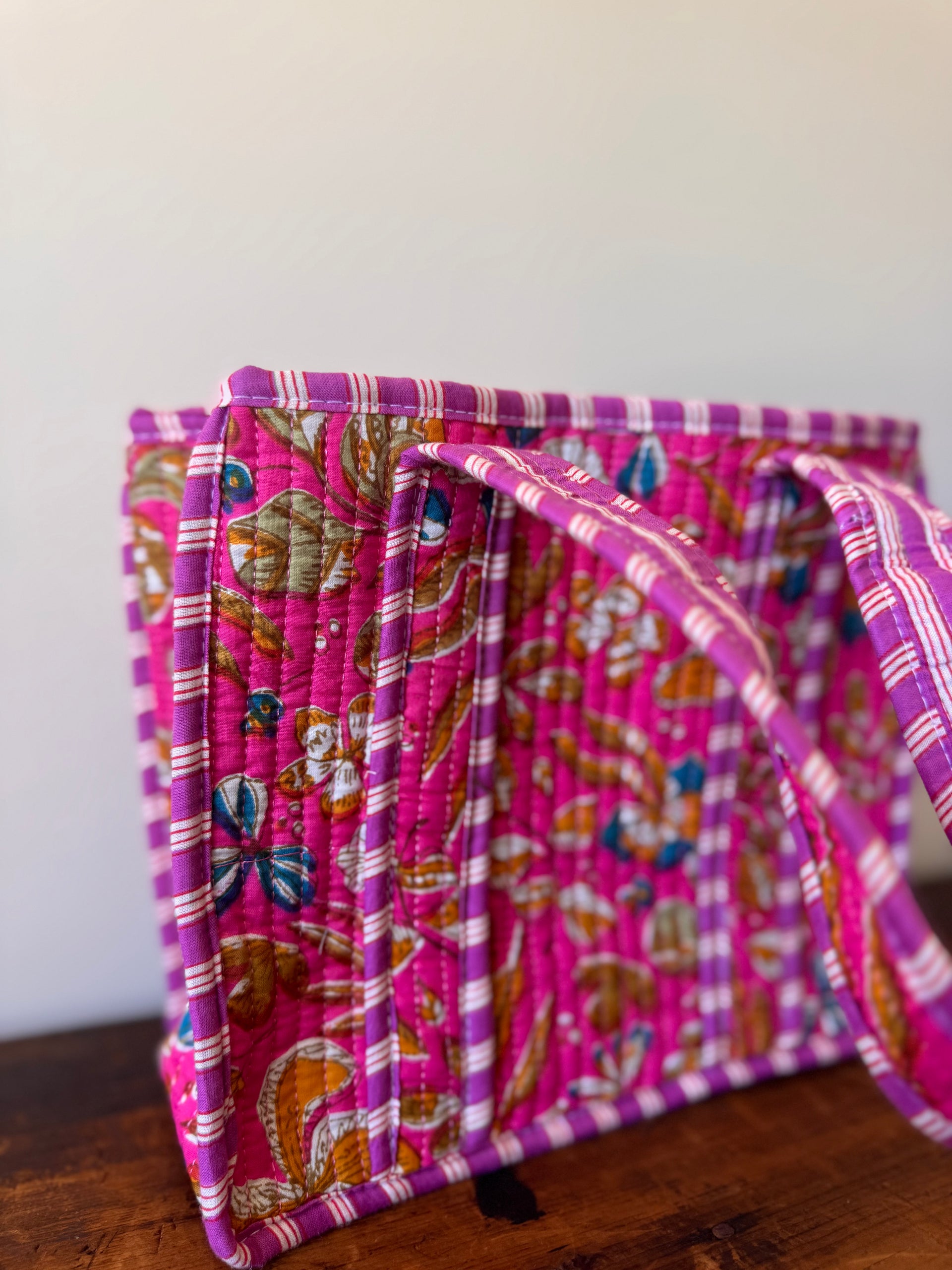 Stack of colorful fabric books on a wooden surface with a white background