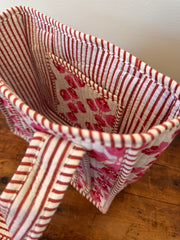 Fabric basket with red and white striped pattern on a wooden surface
