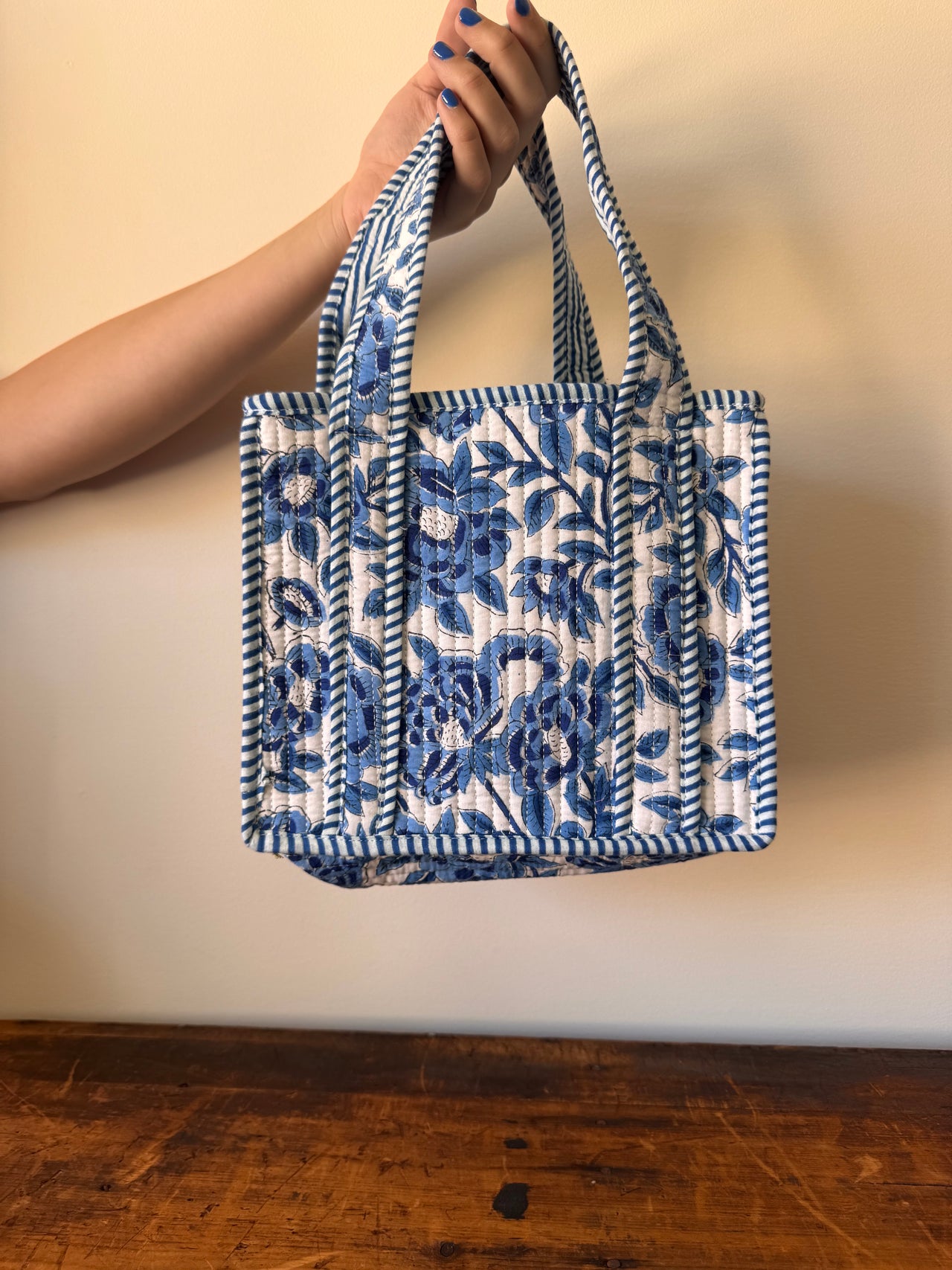 Blue and white patterned bag held by a hand against a neutral background