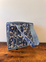 Folded blue and white patterned blanket on a wooden surface