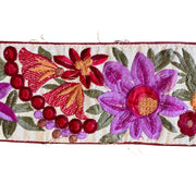 Embroidered floral design with red, purple, and green colors on a white background
