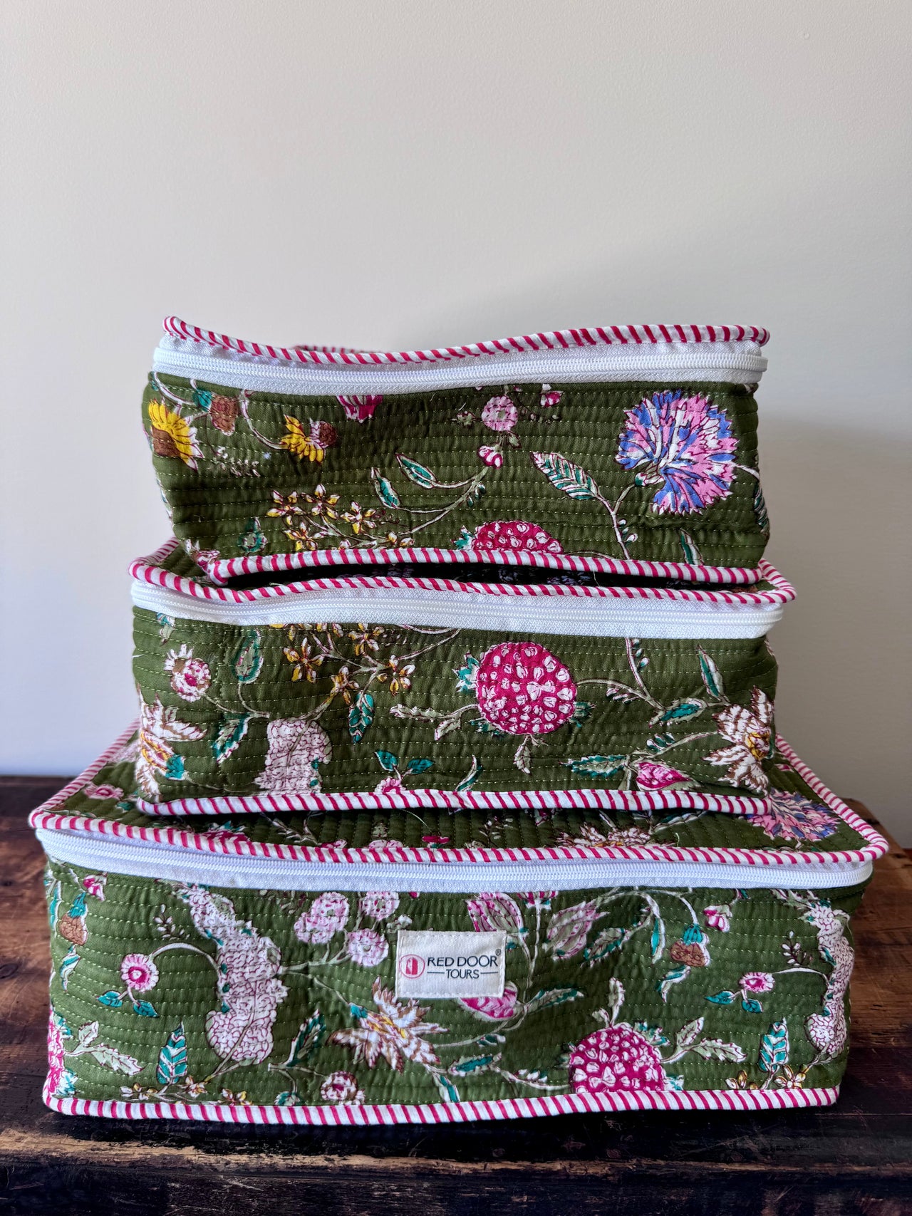 Set of three floral-patterned storage boxes stacked on a wooden surface with a neutral background.