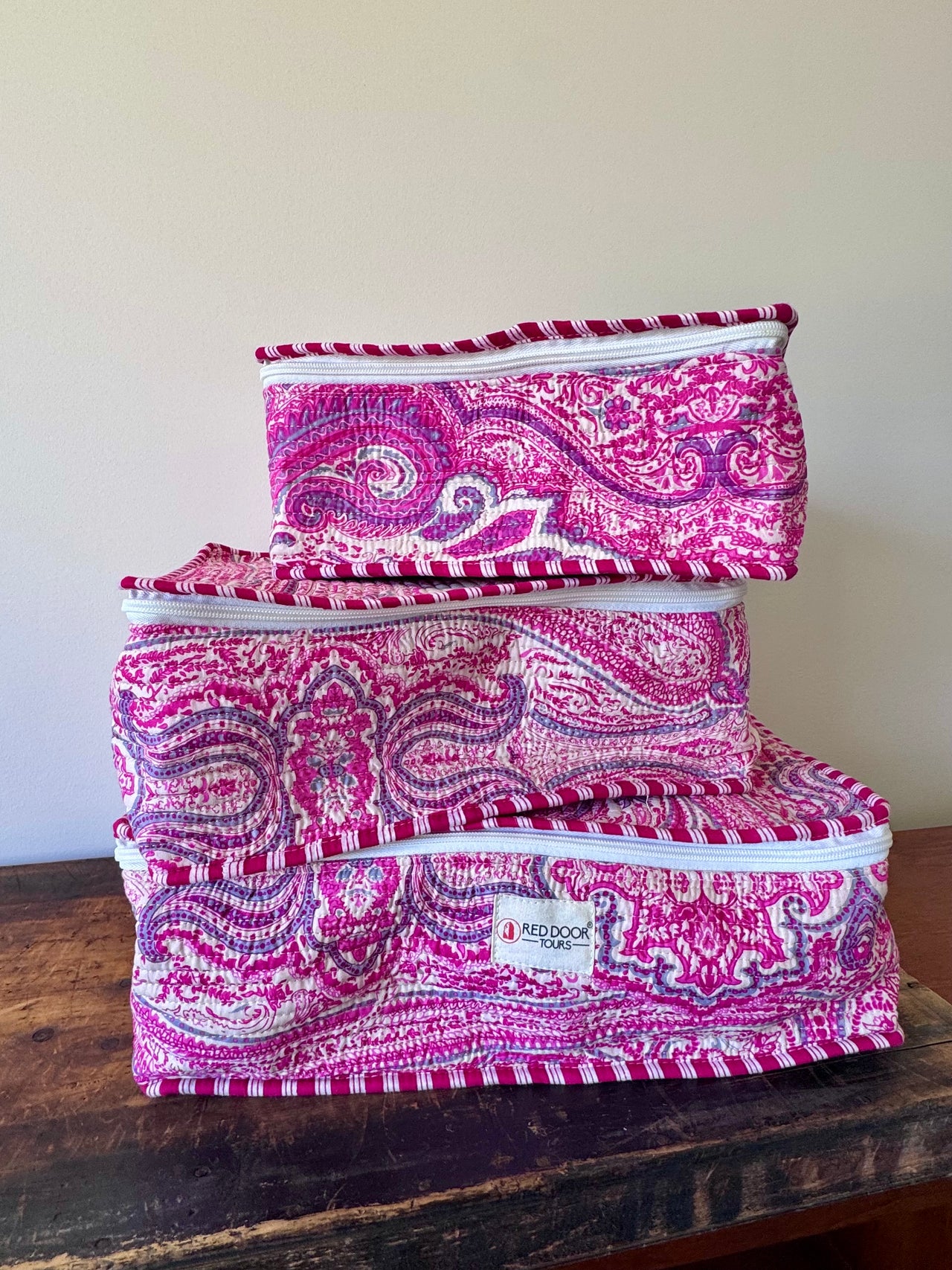 Set of pink and purple patterned fabric bags on a wooden surface with a white background