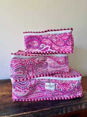Set of pink and purple patterned fabric bags on a wooden surface with a white background