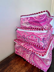 Set of pink and white patterned bags on a wooden floor against a white wall.