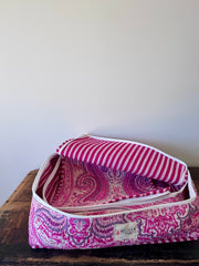 Pink and purple patterned fabric on a wooden surface with a white background