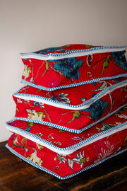 Stack of red fabric containers with floral patterns on a wooden surface