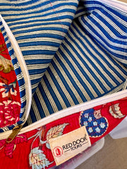Close-up of a red door bag with floral pattern and striped interior, featuring a Red Door Tours label.