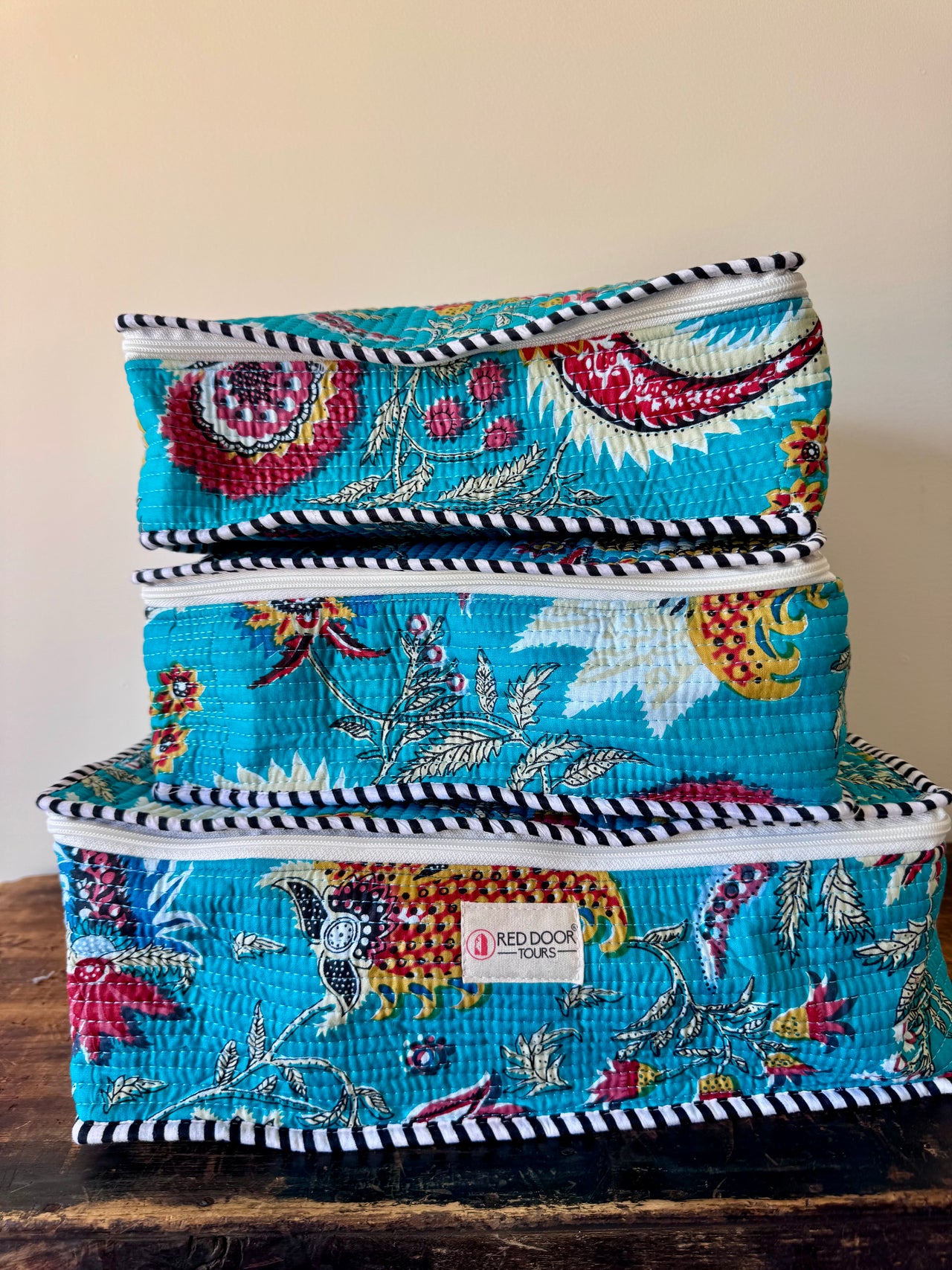 Set of three colorful fabric storage boxes stacked on a wooden surface.