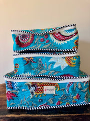 Set of three colorful fabric storage boxes stacked on a wooden surface.