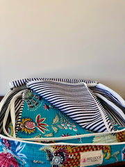 Colorful suitcase with floral and striped fabric on a white background