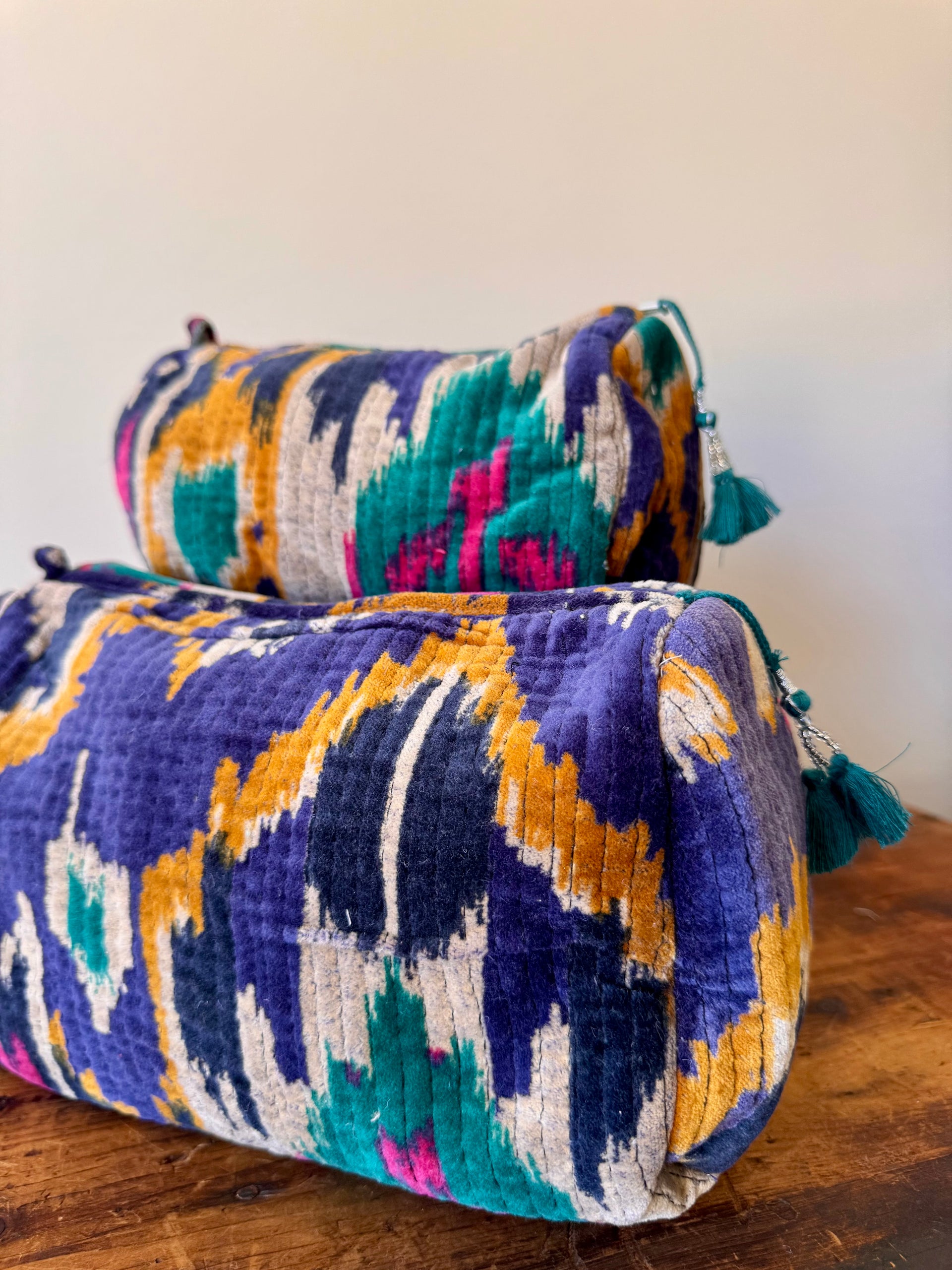 Two colorful patterned bags on a wooden surface with a white background