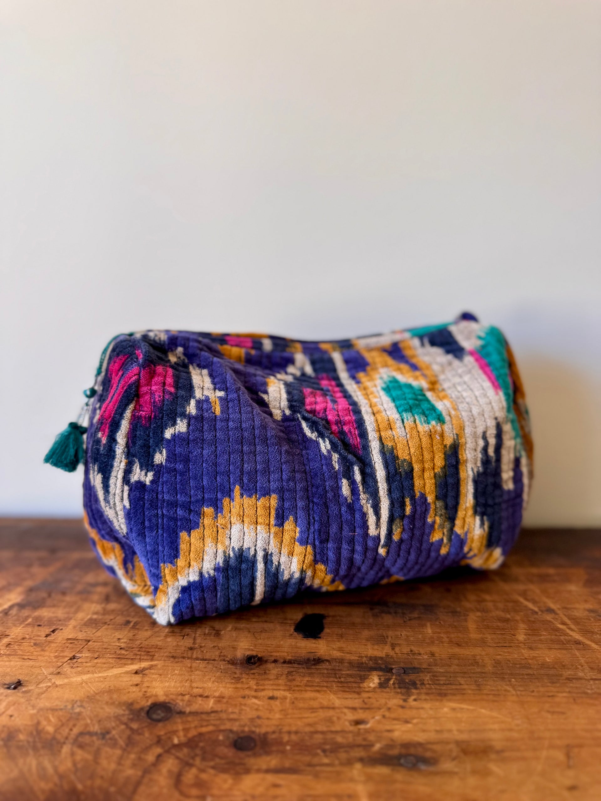 Colorful patterned pouch on a wooden surface with a white background