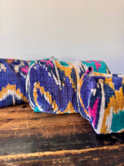 Colorful patterned fabric roll on a wooden surface with a white background