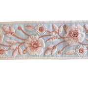 Embroidered floral ribbon with pink flowers on a light blue background
